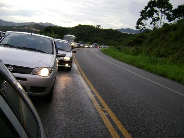 Carros com faróis ligados na estrada durante o dia