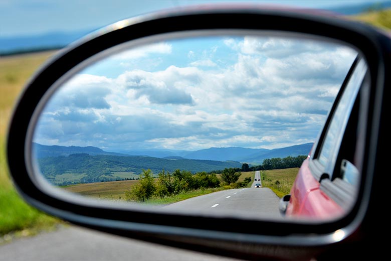 Imagem de um retrovisor que mostra tanto a lateral do carro, quanto a estrada