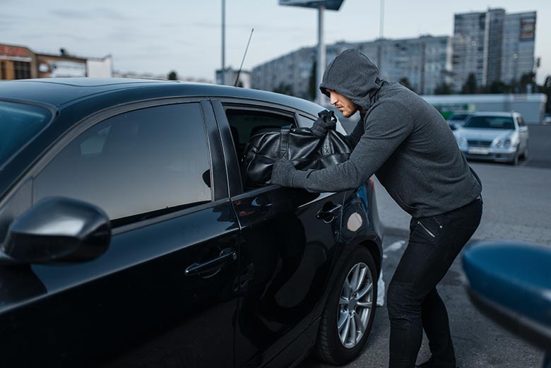 Criminoso furtando bolsa de dentro de um carro